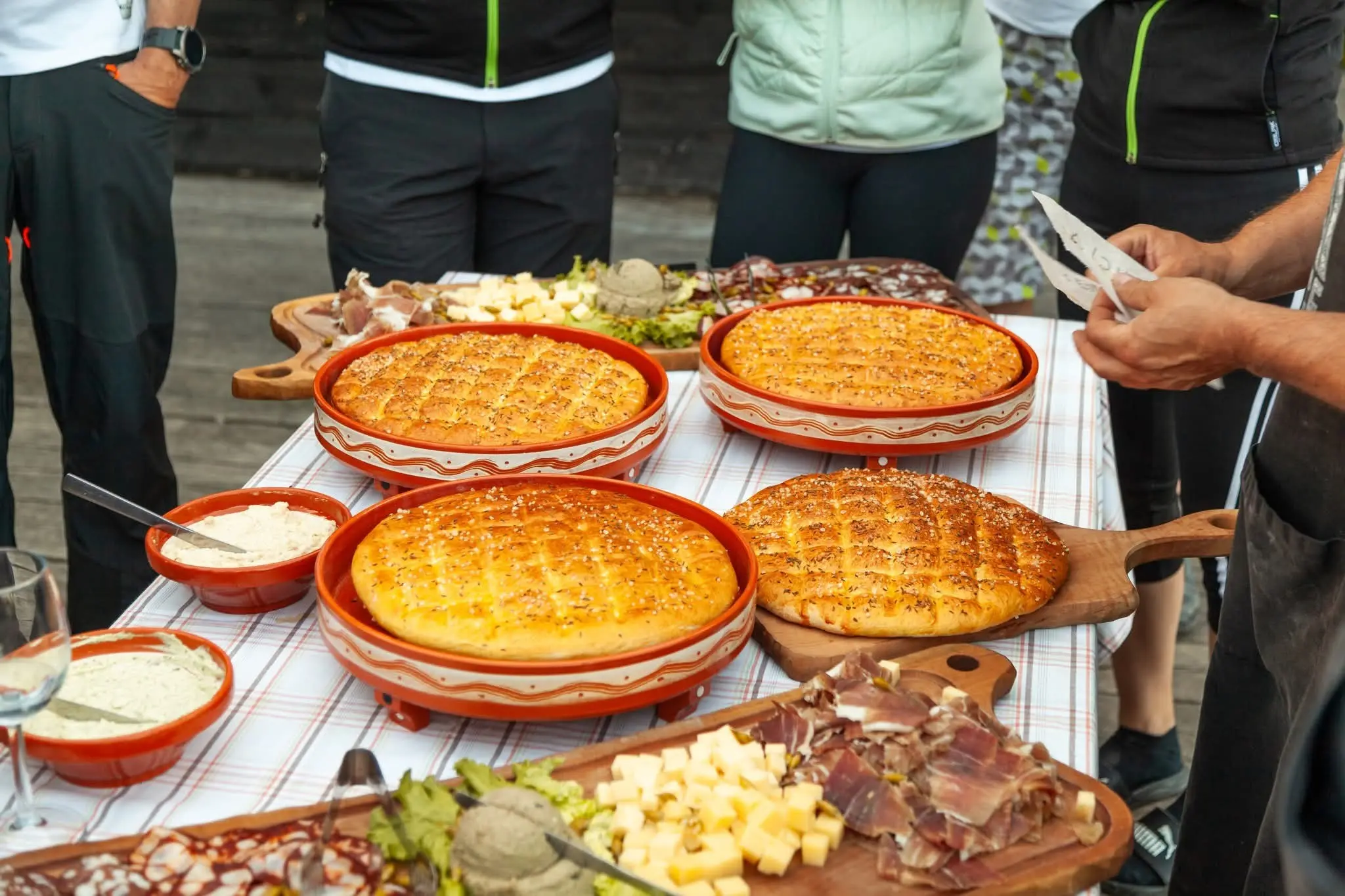 Miza polna slovenskih jedi, vključno z domačim kruhom, narezki in siri.