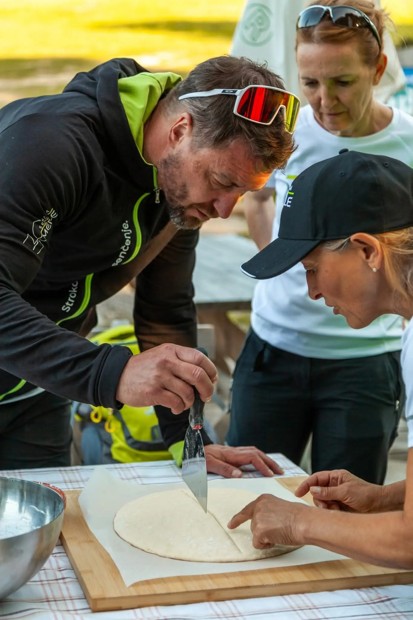 Skupina ljudi se osredotoča na rezanje testa na mizi.